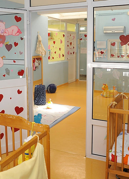 Preschool classroom with cribs, toys, and colorful decorations