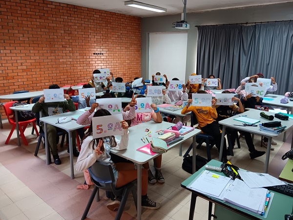Students in a classroom holding signs with numbers and letters