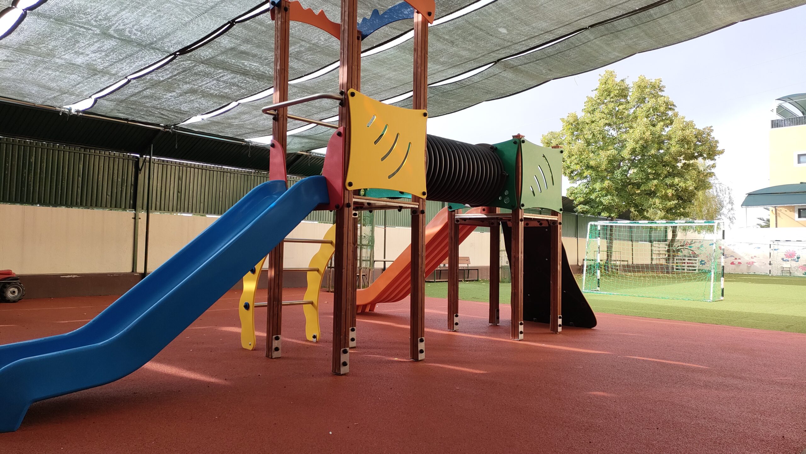Preschool playground with colorful play structures and a shaded area