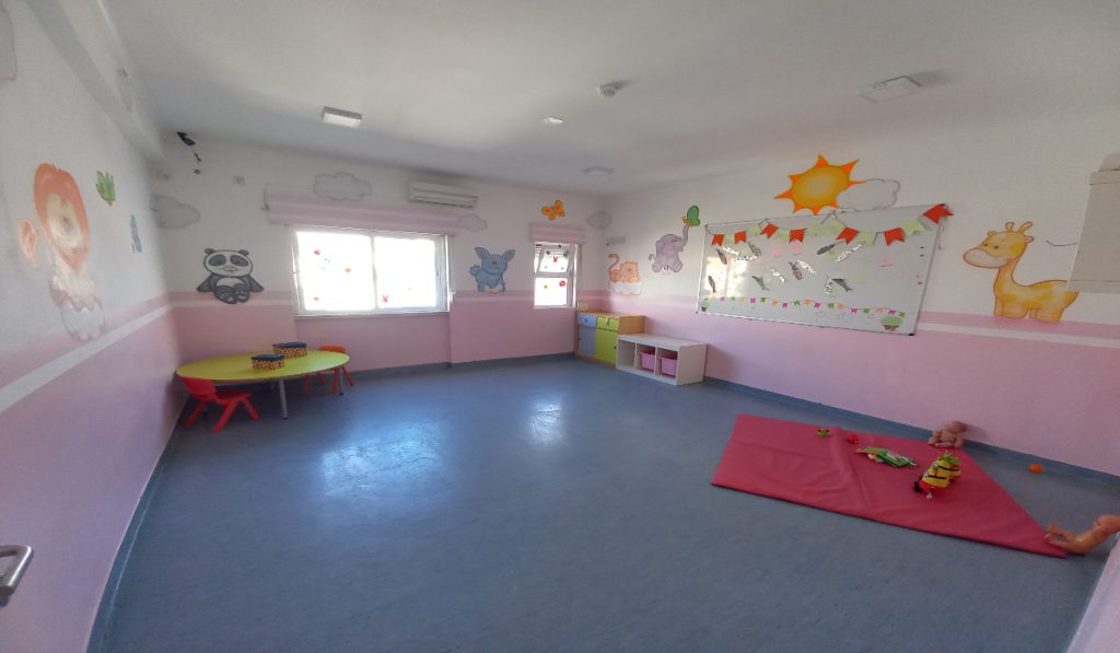Preschool classroom with pink walls, animal murals, and children's furniture