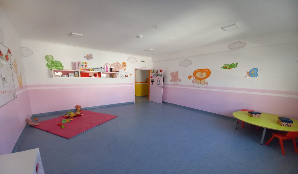 Preschool classroom with pink walls, animal murals, and children's toys
