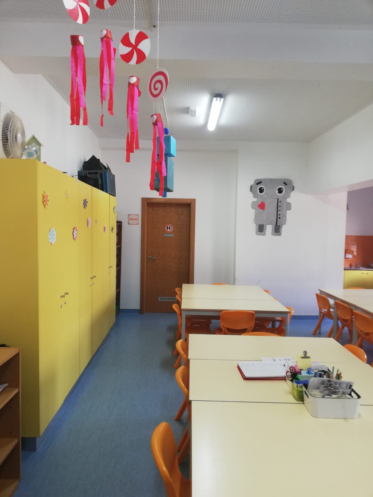 Preschool classroom with tables, chairs, and colorful decorations