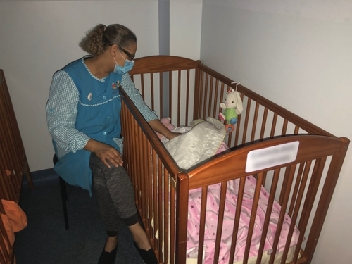 Teacher caring for a baby in a crib at The Cachoeirinhos Nursery and Kindergarten
