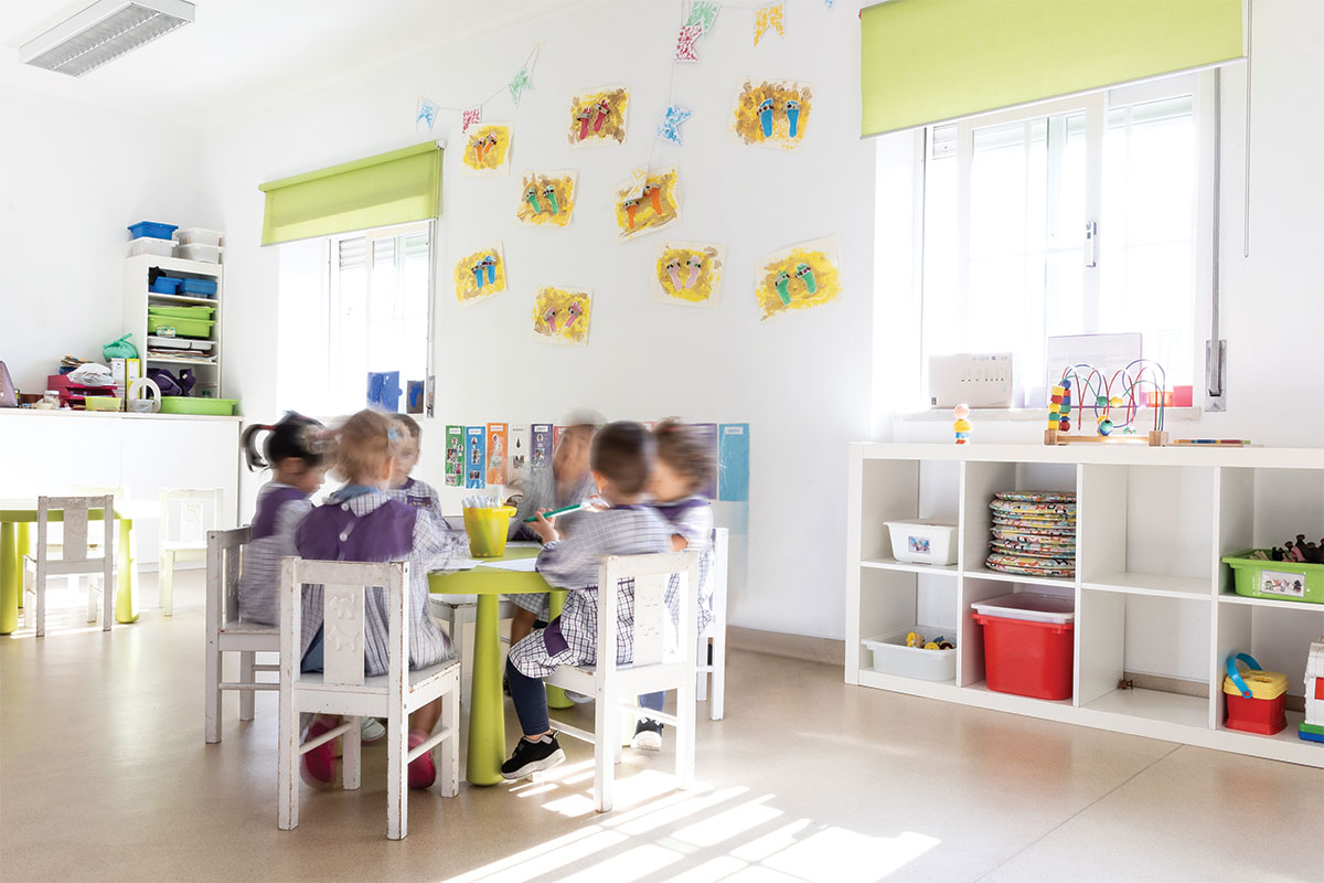 Preschool children sitting at a table in a classroom, engaged in an activity.