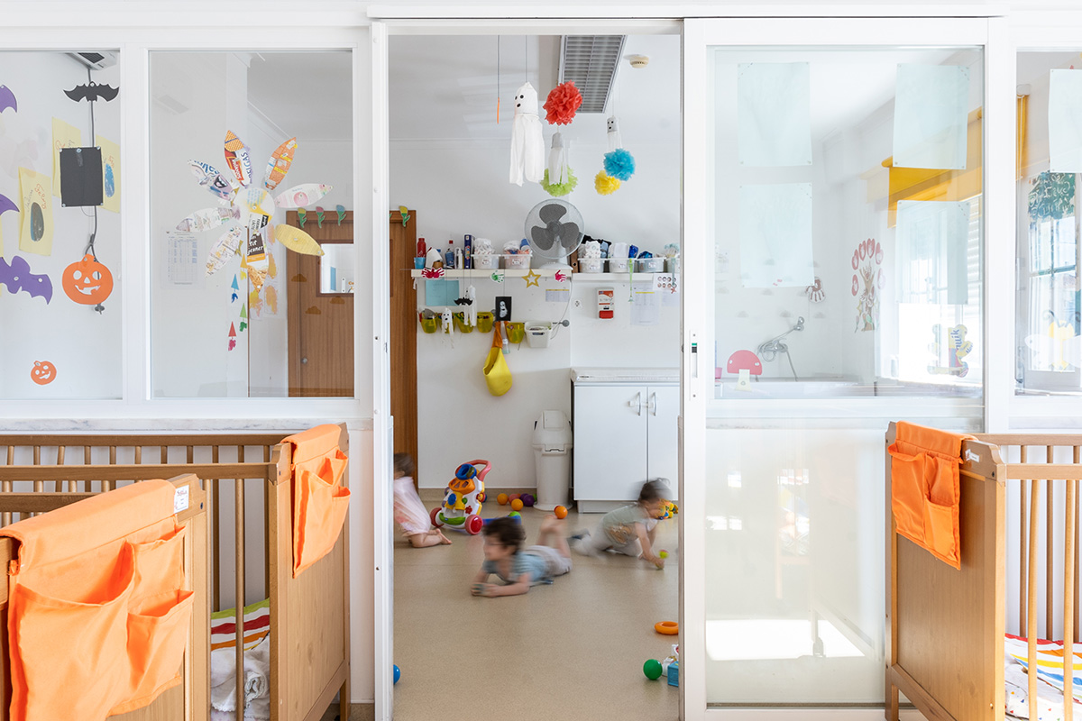 Preschool classroom with children playing and cribs