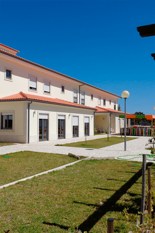 Exterior view of AMOP preschool building, showing the building's architecture, landscaping, and playground equipment.