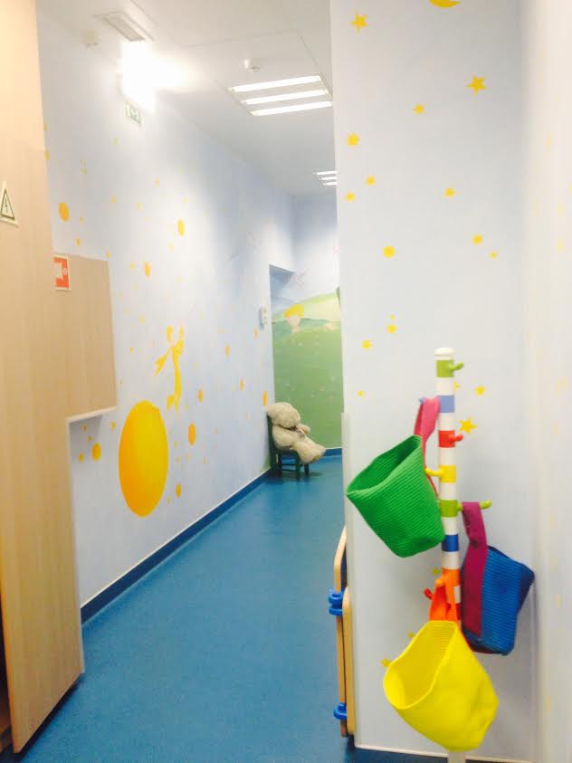 Interior hallway of O Bom Principezinho preschool with The Little Prince-themed wall decor and colorful storage bins.