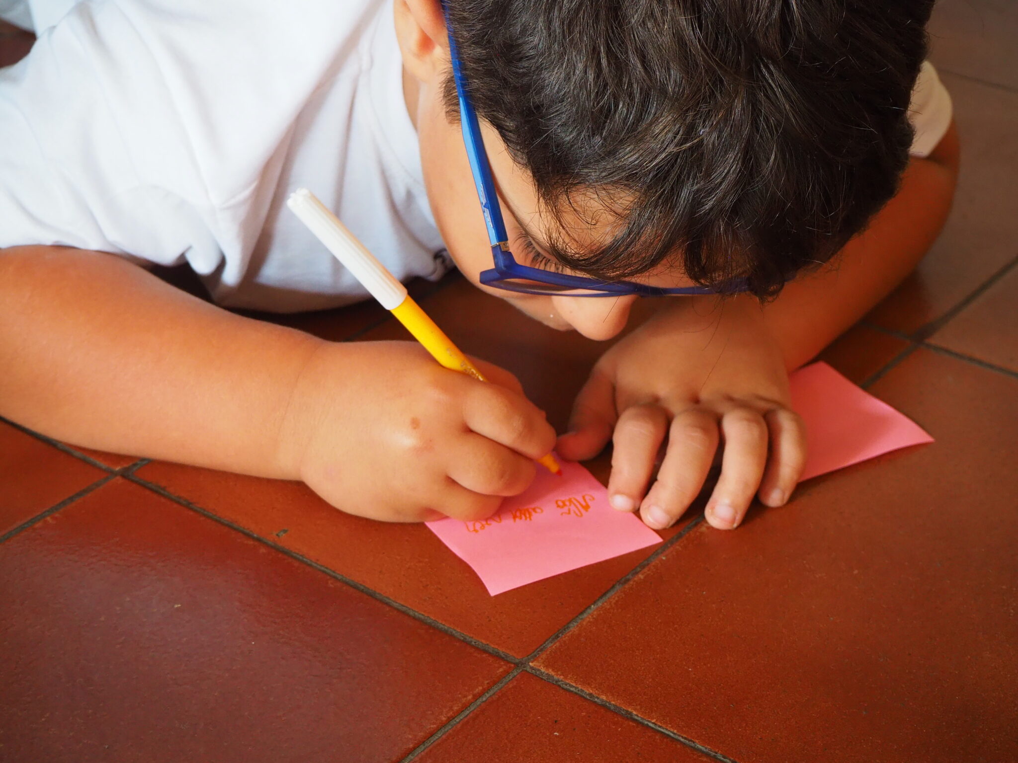 Preschool child writing on a pink paper