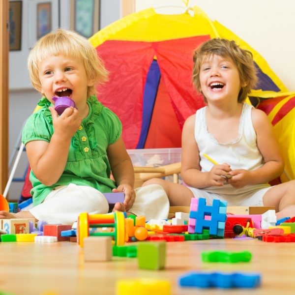 Two preschool children playing with colorful toys in a playroom