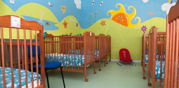 Preschool nap room with cribs and colorful wall mural