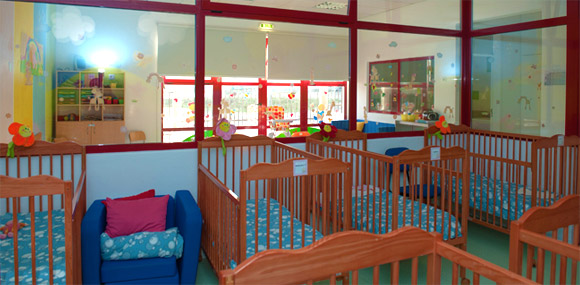 Infant room with cribs and colorful decorations at Arco-íris Preschool