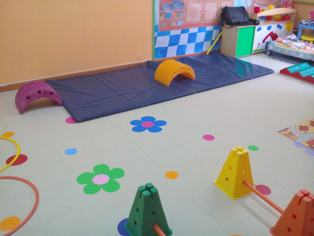 Preschool playground with colorful mats, hurdles, and floor markings