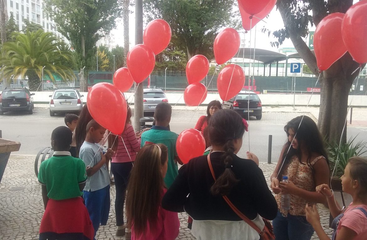 Preschool children holding red balloons