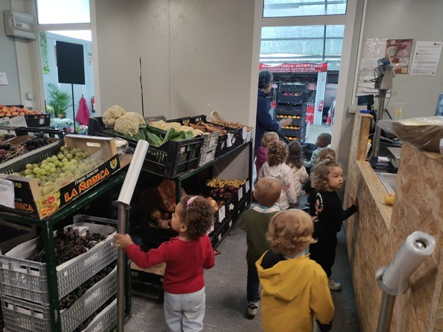 Preschool children on a field trip to a local market, learning about fruits and vegetables.