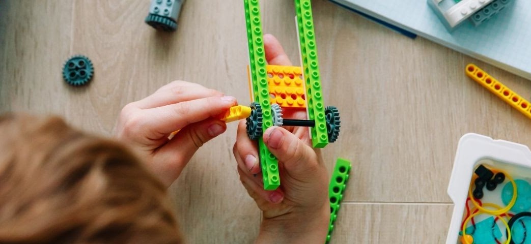 Preschool child building with colorful LEGO-like blocks.