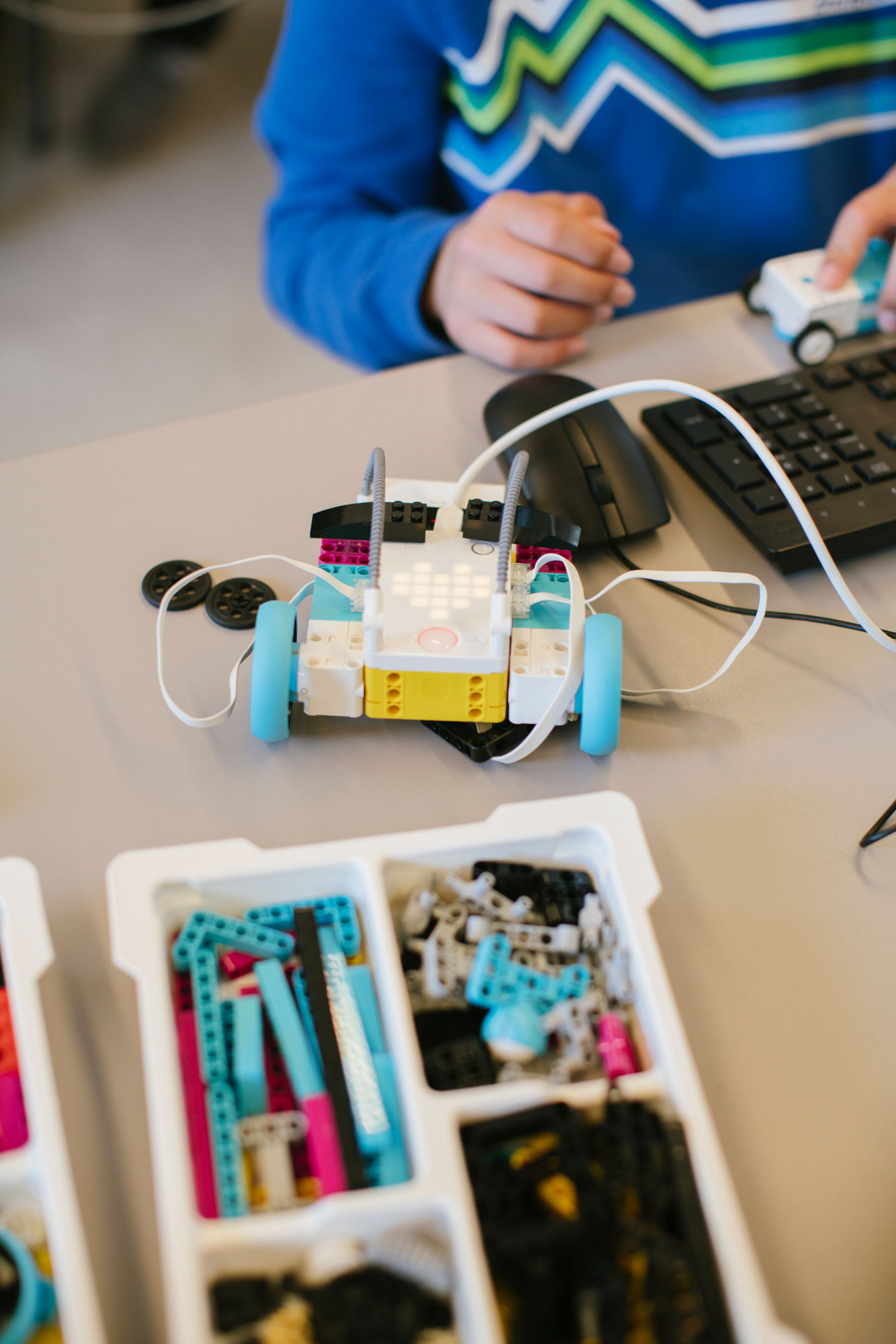 Student building a robot with colorful LEGOs during a robotics class.