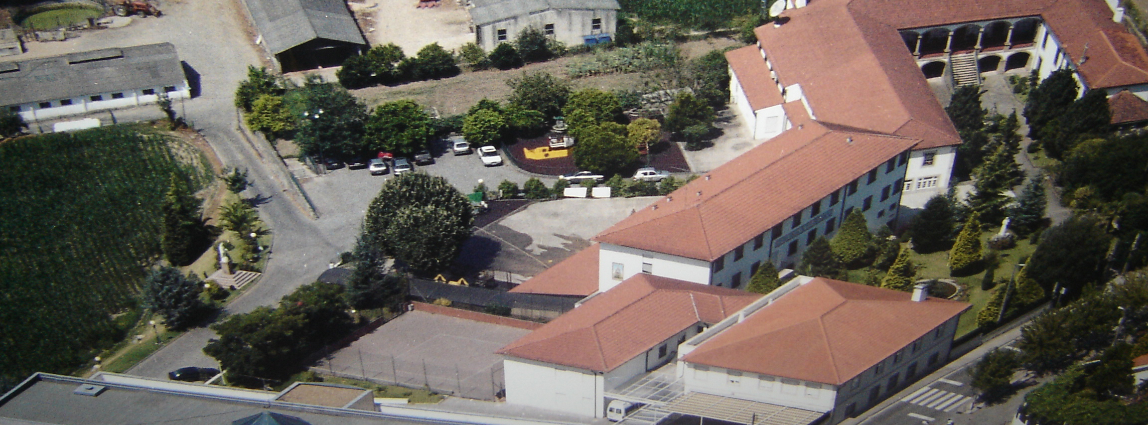 Aerial view of Colégio Nossa Senhora das Graças school campus, showing buildings, playground, and parking lot.