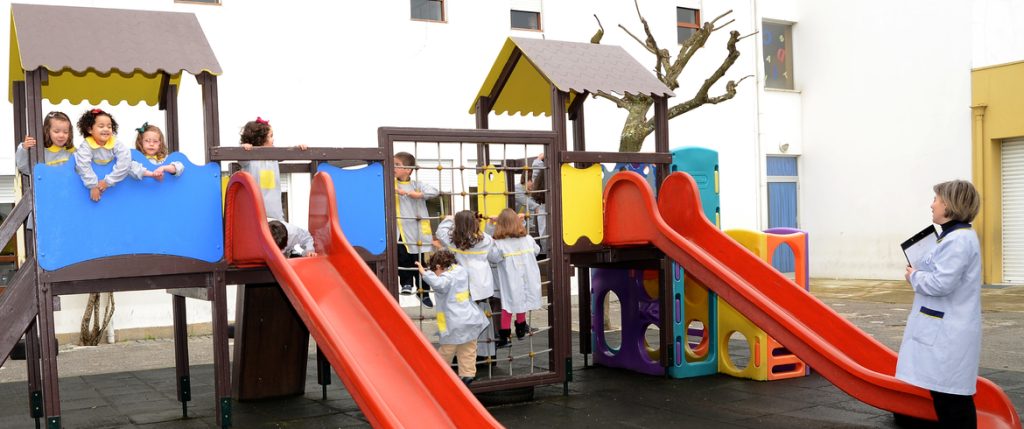 Preschool children playing on a playground, supervised by a teacher