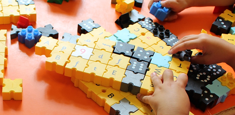 Preschool children engaging in a hands-on learning activity with colorful blocks and puzzles.