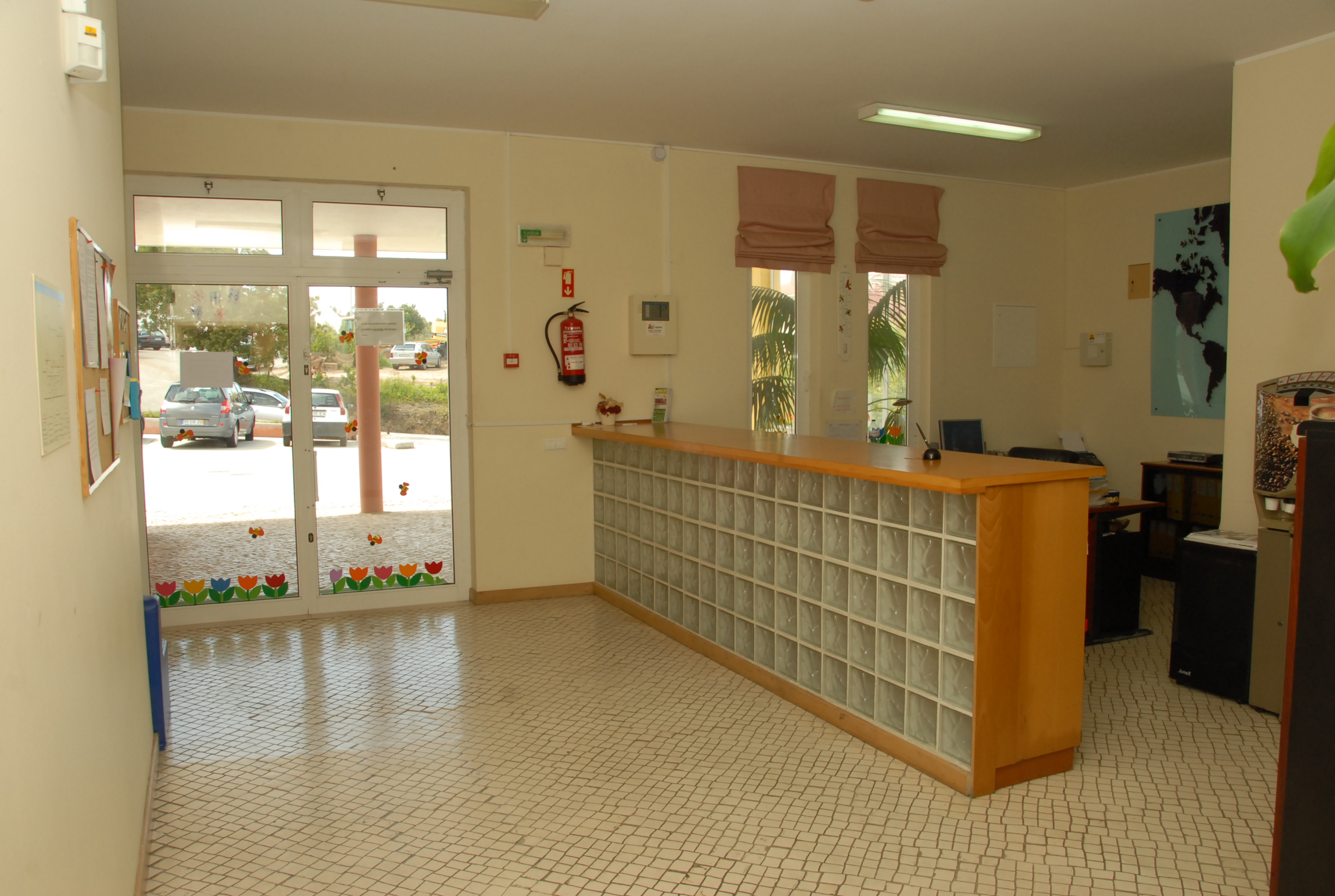 Reception area of Creche Colégio de S. Vicente preschool with a wooden counter and glass block wall