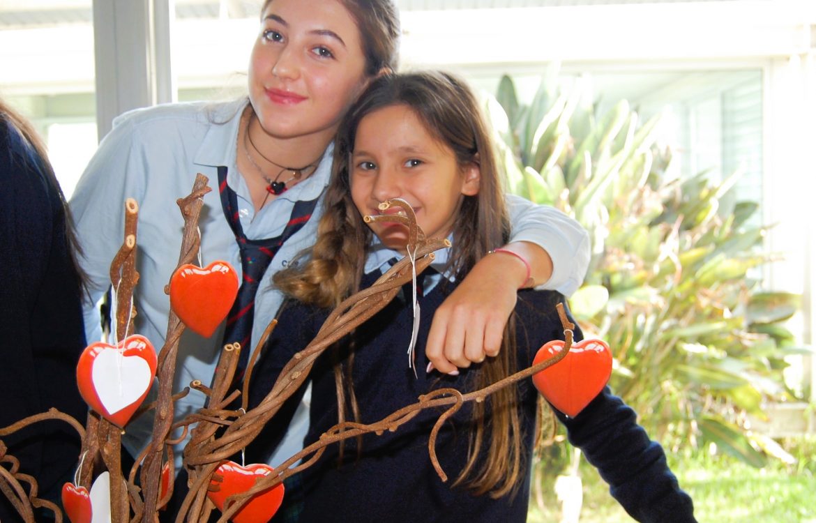 Two students at CLIB International School of Braga posing together with a decorative heart-shaped tree