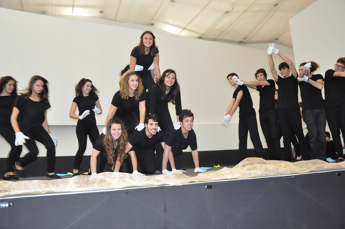 Students participating in a school performance, wearing black clothing and white gloves.