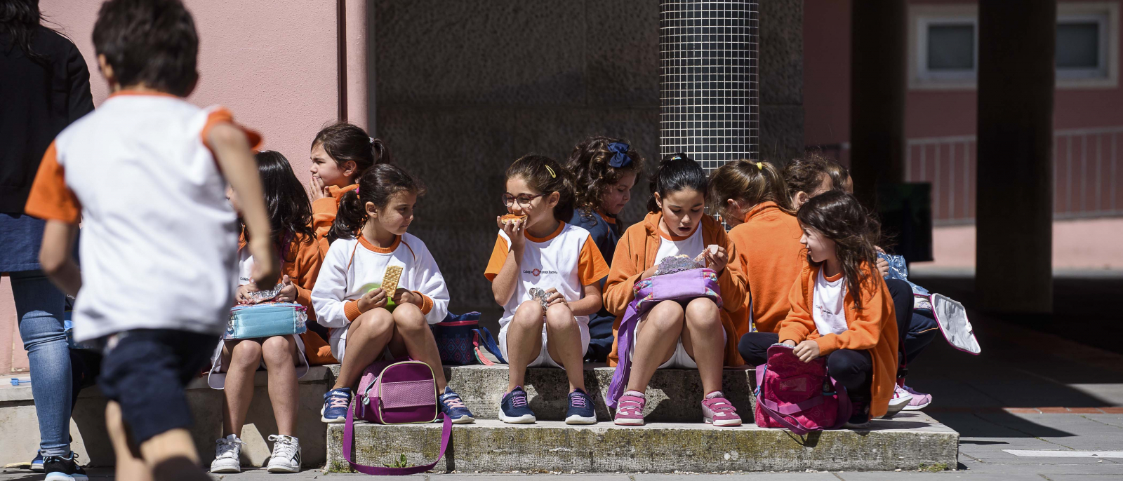 Students sitting on steps at Colégio Bissaya Barreto, eating snacks.