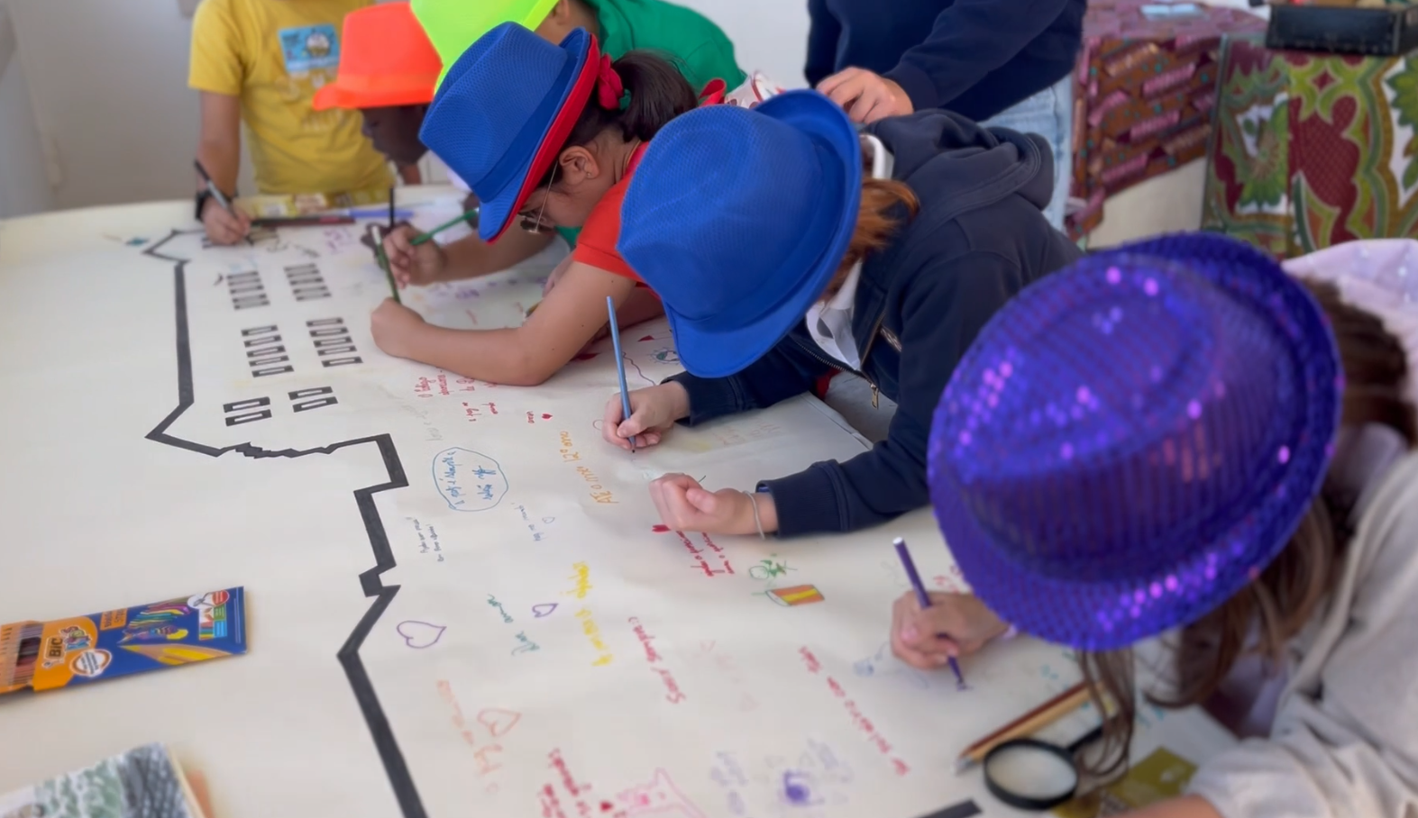 Preschool children drawing on a large paper depicting the school building