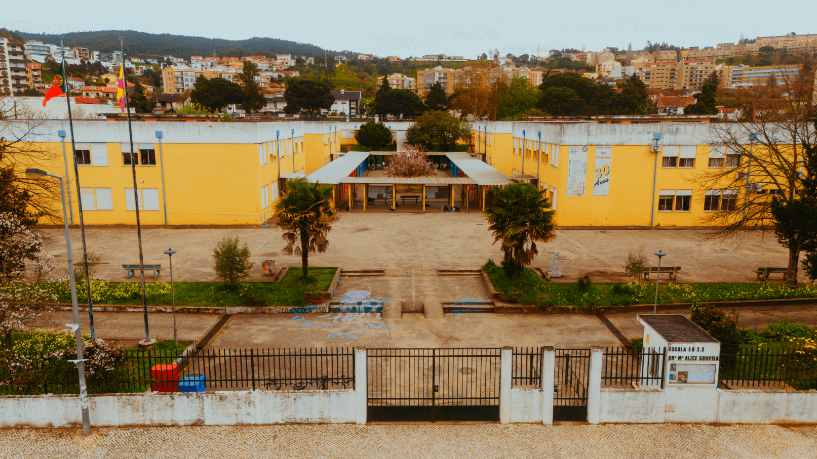 Exterior view of Coimbra Sul School Group, showing the yellow school building, playground, and surrounding area.
