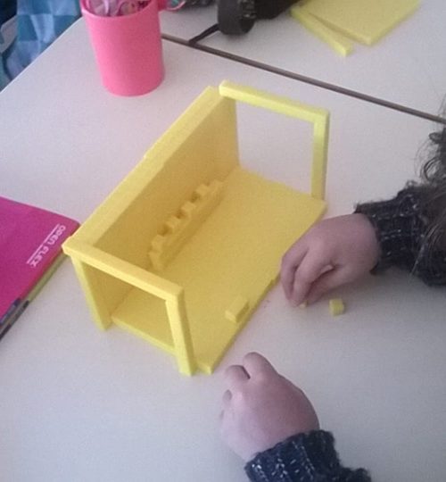 Preschool student building a yellow structure with blocks