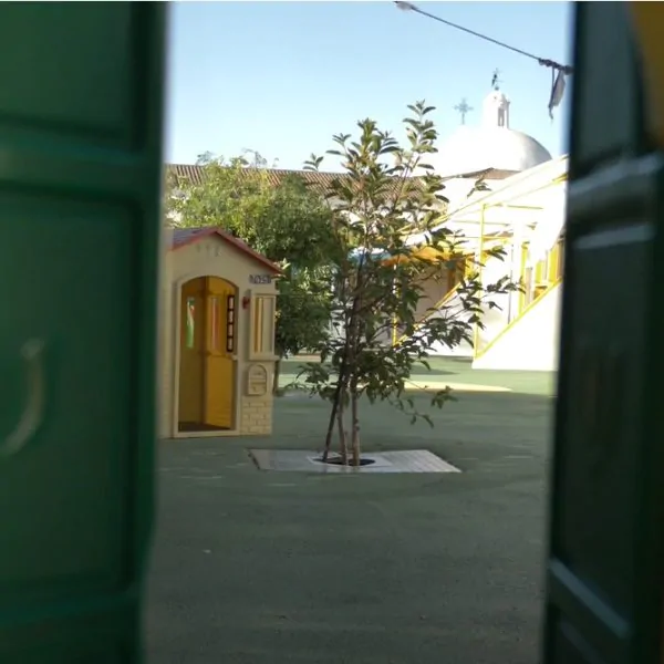 Infantário Pimpão outdoor play area with a small playhouse and trees
