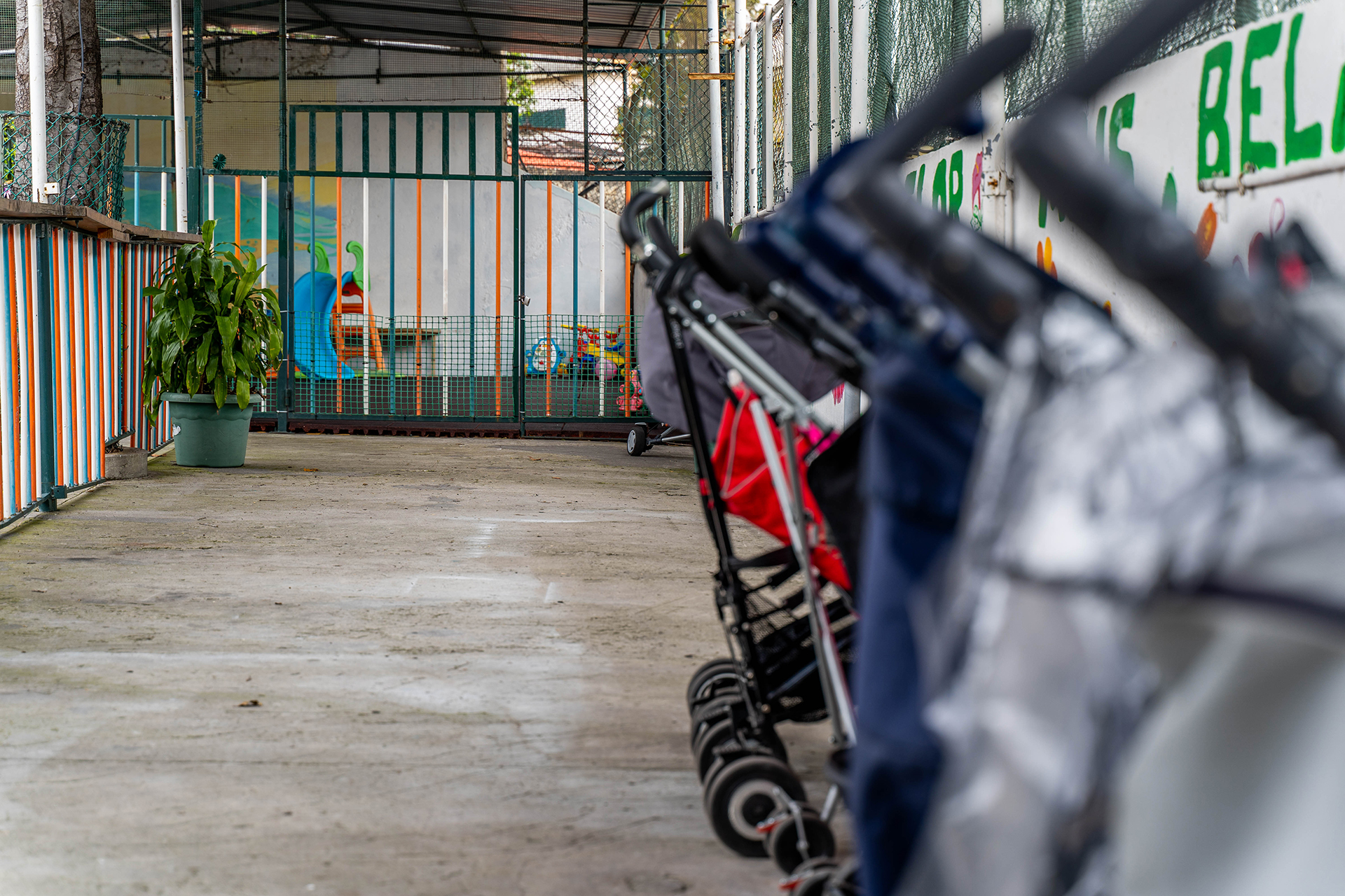 Exterior view of Jardim de Infância do Patronato de São Pedro preschool, showing playground equipment and strollers parked outside.