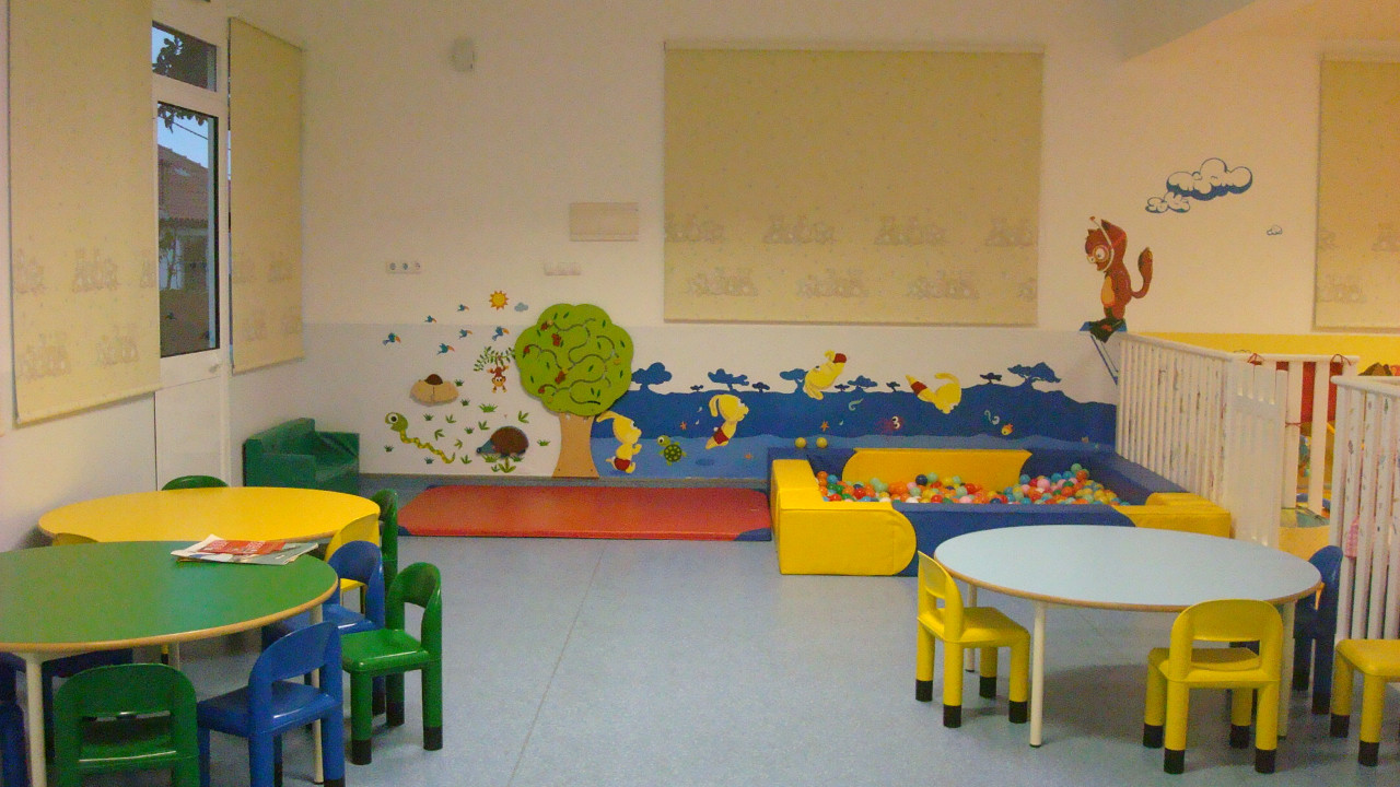 Preschool classroom with colorful tables, chairs, and a ball pit