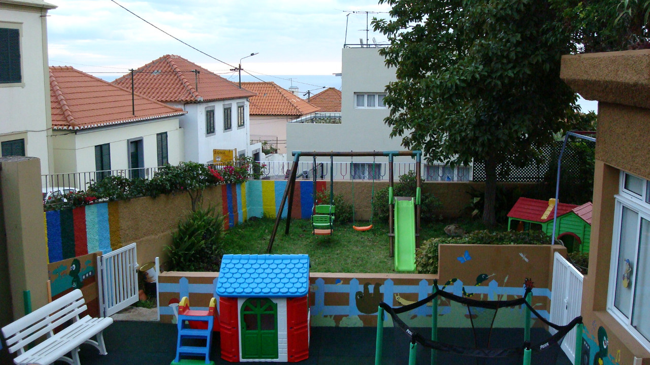 Preschool playground with swings, slide, and playhouse