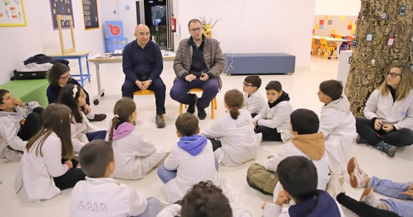 Preschool children sitting in a circle with two adults, participating in a science lesson