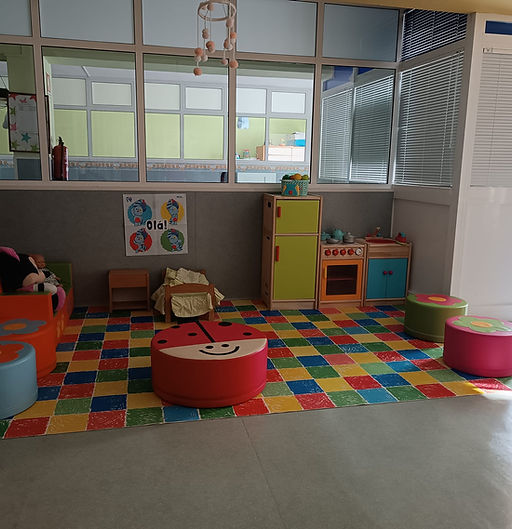 Preschool playroom with colorful floor, toy kitchen, and soft seating