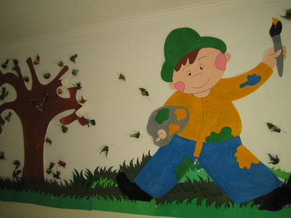 Colorful artwork depicting a painter and a tree adorns a preschool wall.