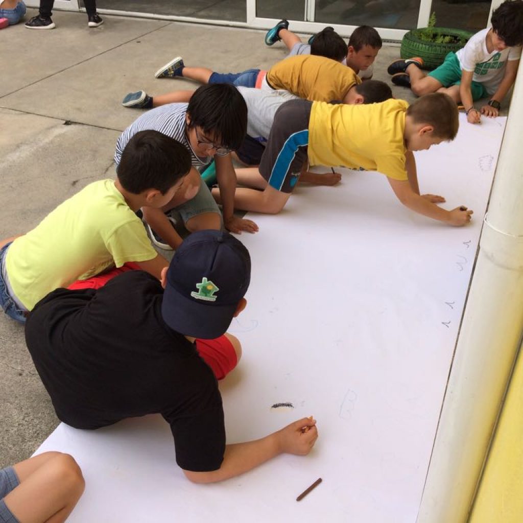 Preschool children collaboratively drawing on a large sheet of paper.