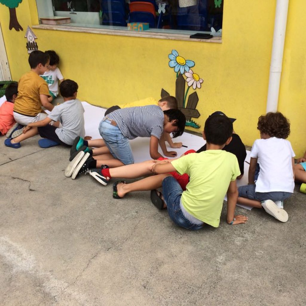 Preschool children collaborating on a large art project outdoors