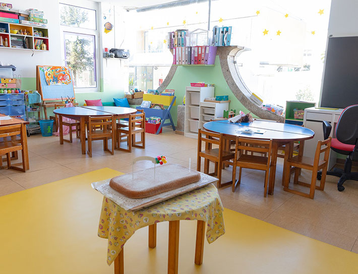 Preschool classroom with colorful tables and chairs, and learning materials