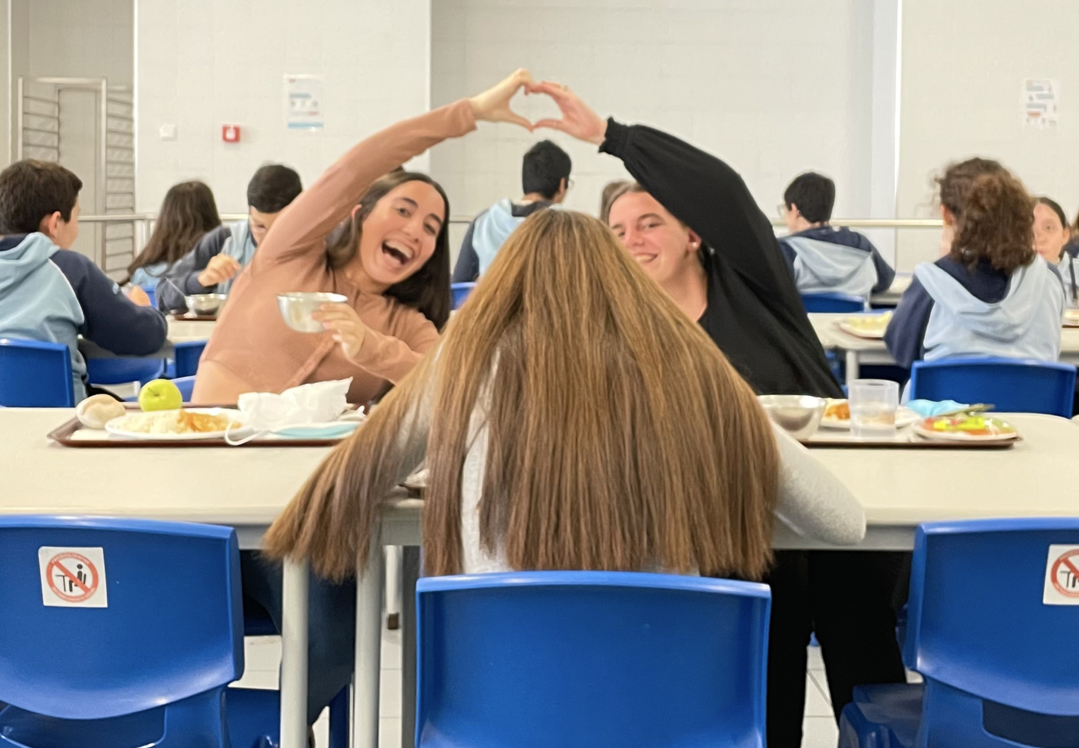 Students making a heart shape with their hands during lunch break at school