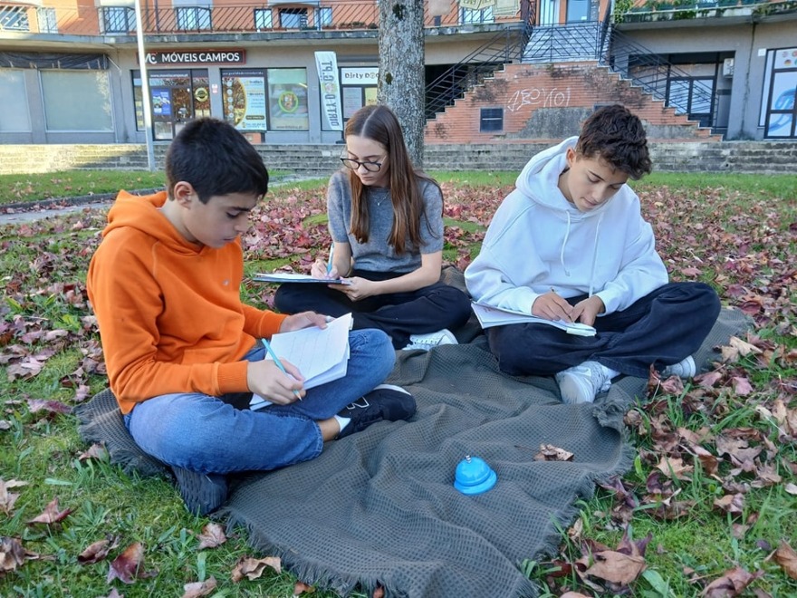 Three students studying outdoors on a blanket, demonstrating outdoor learning at The Anglophil Centre.