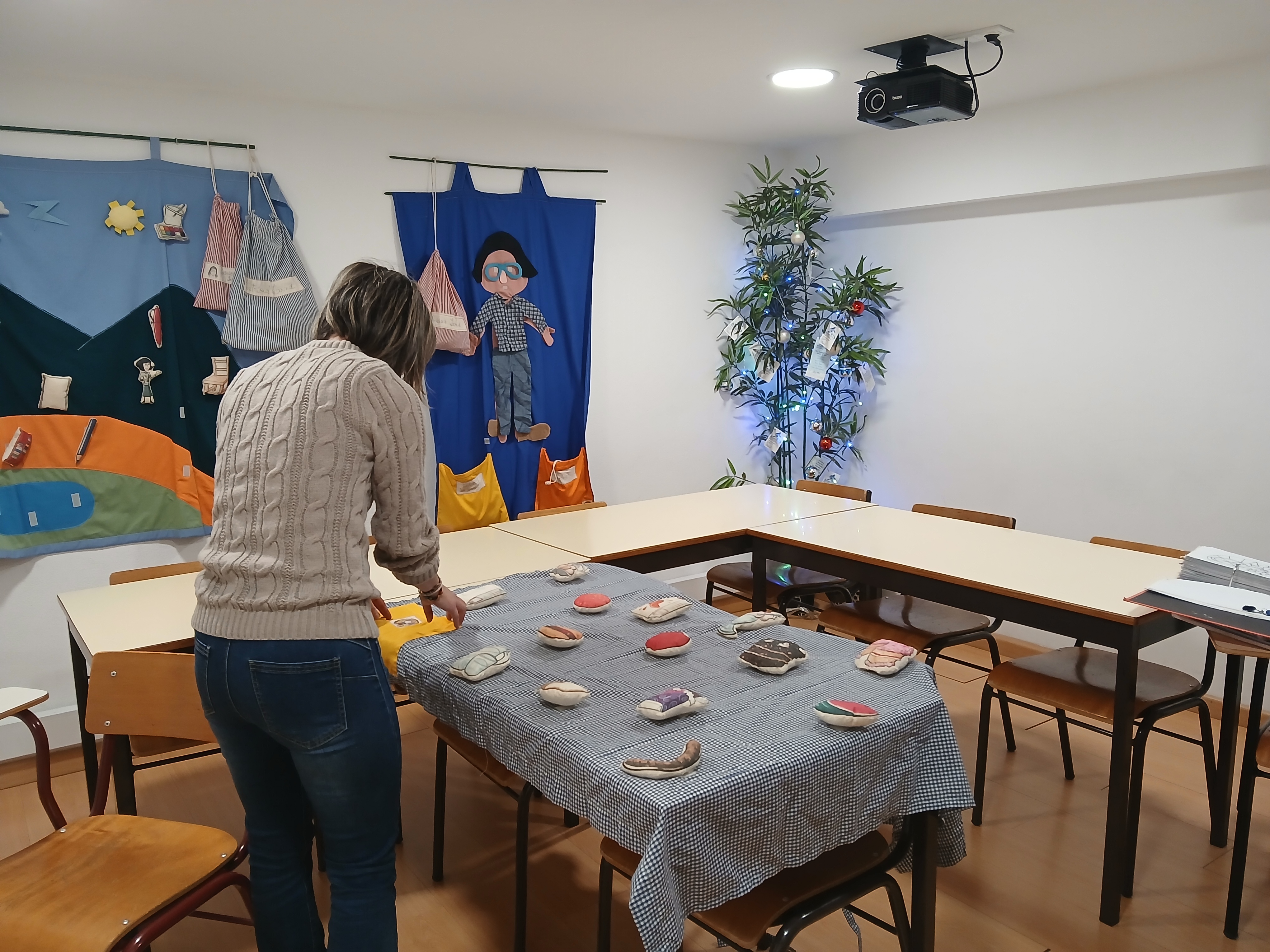 Preschool teacher arranging food-themed stuffed toys on a table