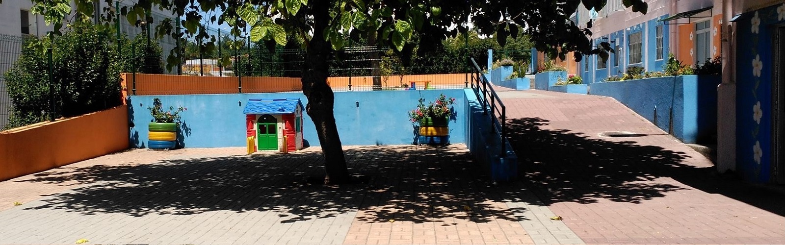Preschool playground with colorful playhouse and tire planters
