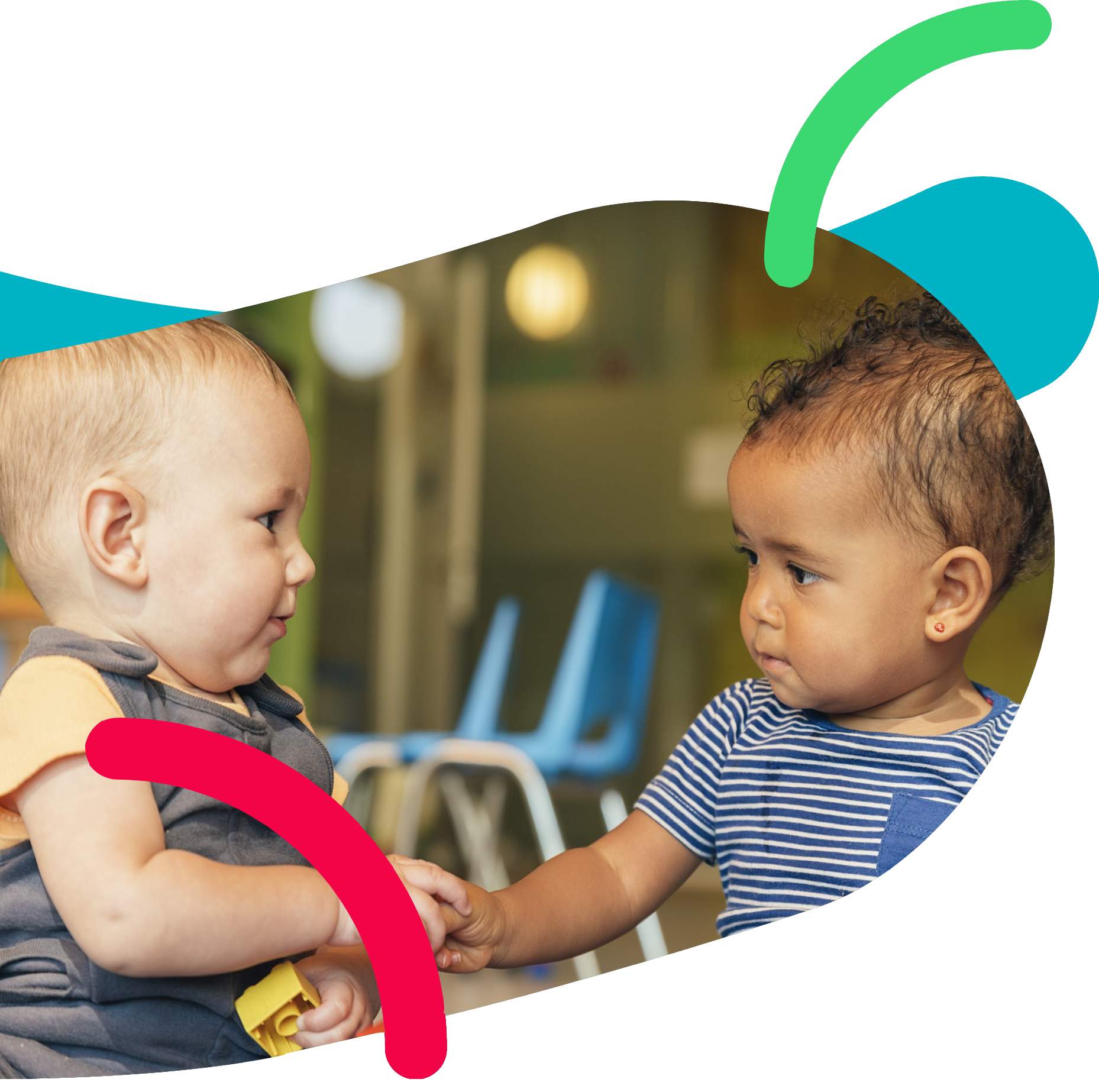 Two toddlers holding hands and playing together in a preschool classroom