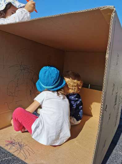 Preschool children drawing on a cardboard box