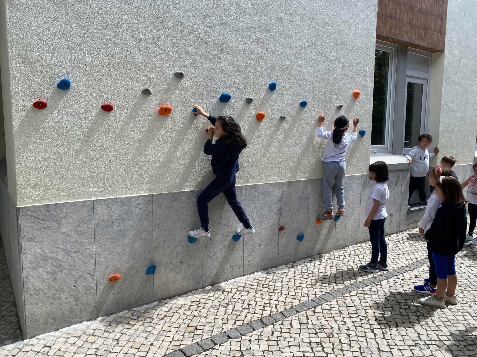 Preschool children enjoying outdoor playtime on a climbing wall
