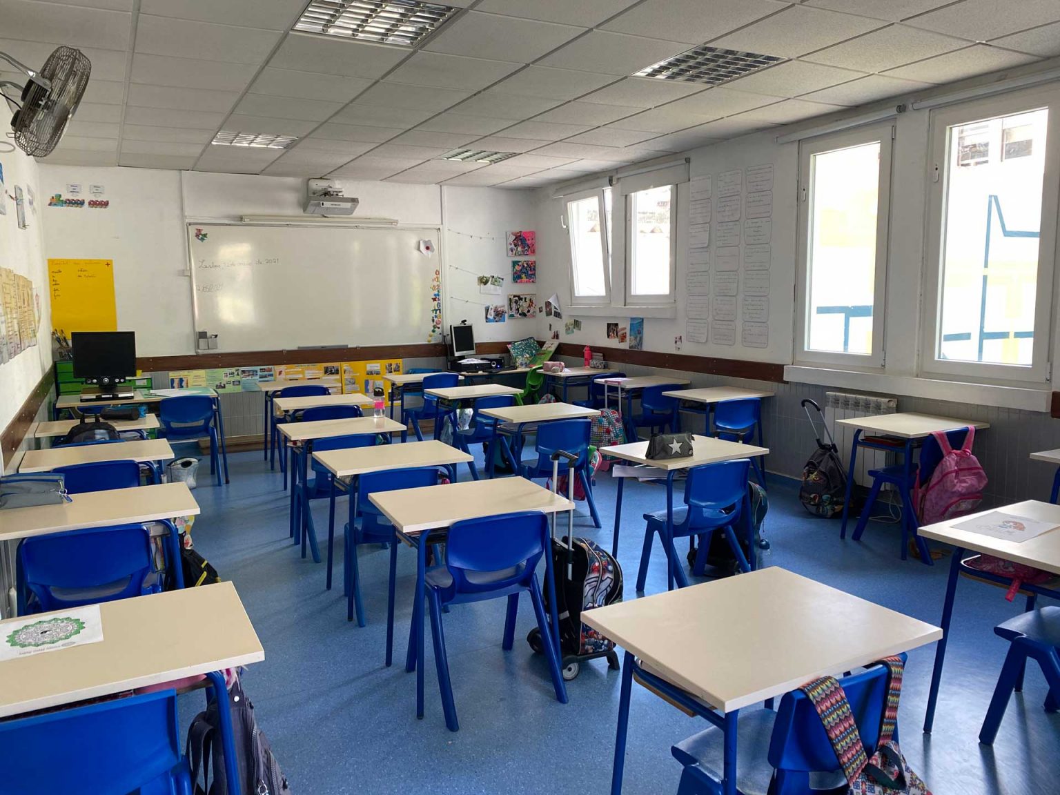 Empty classroom with blue chairs and tables, ready for students