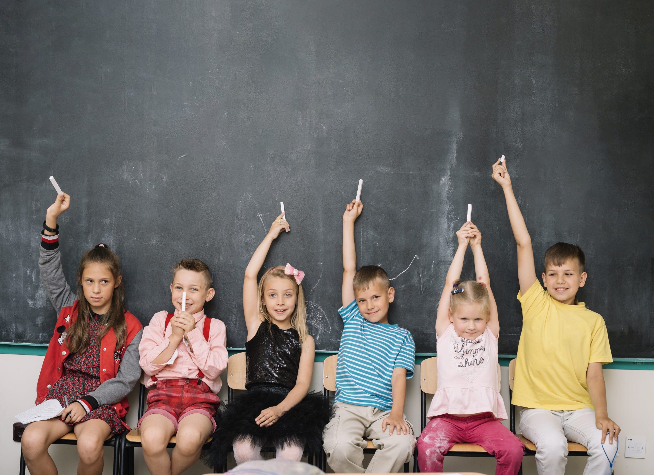 Preschool children raising their hands in class