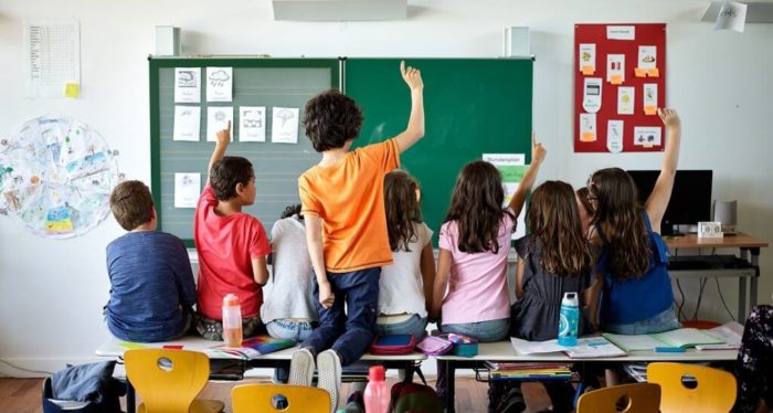 Elementary school children actively participating in a classroom lesson.